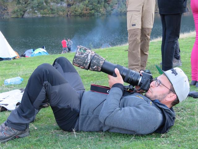 Un membre du club allongé dans l'herbe photographie au téléobjectif